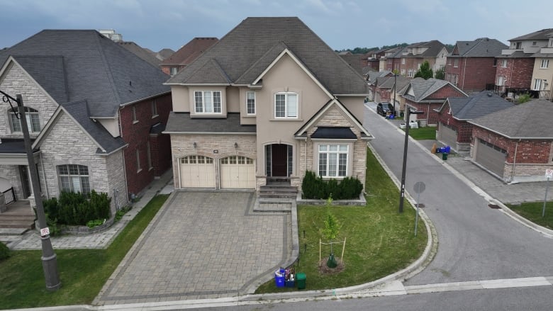 A large home on a corner lot in a residential neighbourhood is pictured from above. 