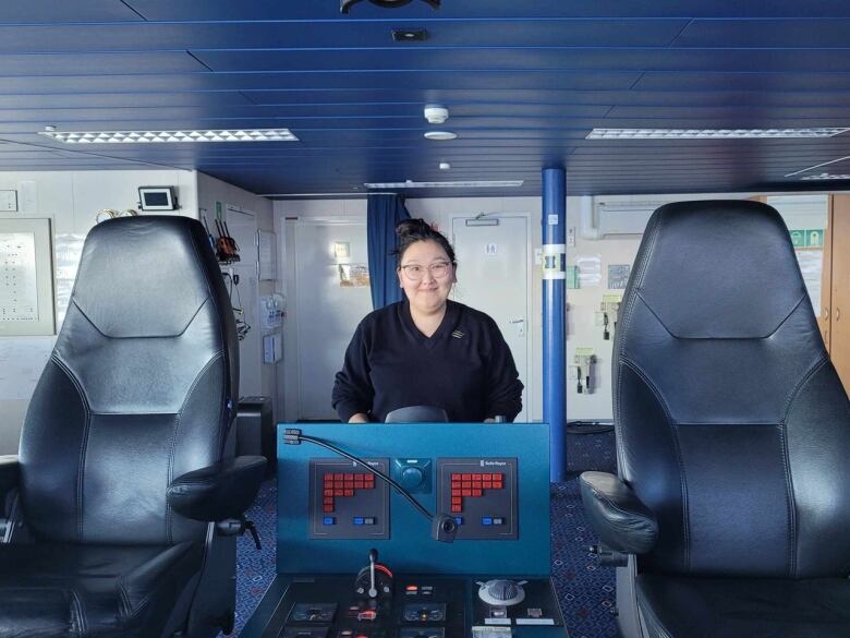 A girl smiles on what looks to be the inside of a ship 