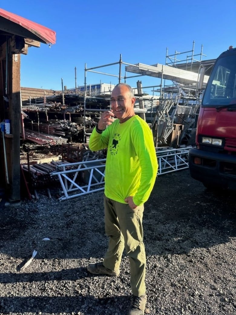 A man wearing a green shirt in a worksite.