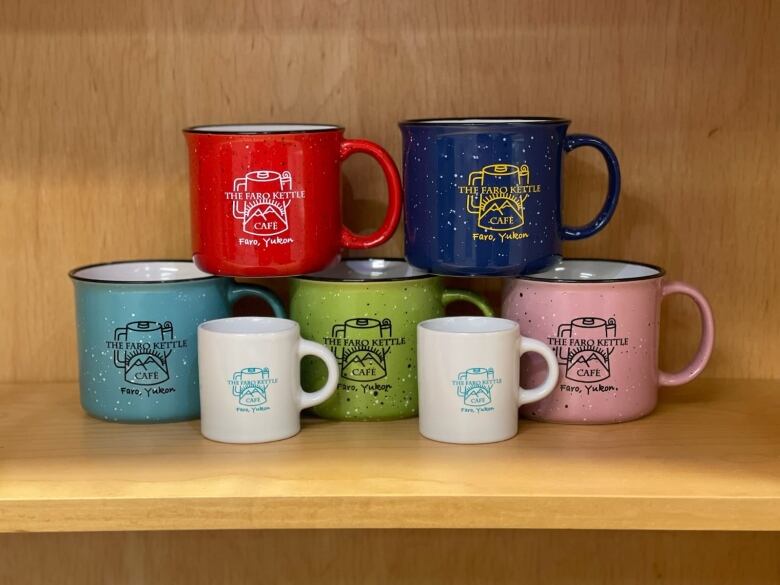 Some merchandise from the Kettle Cafe, different coloured mugs on display. 