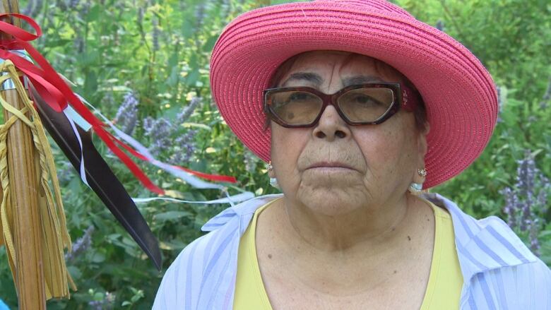 A woman wearing glasses and a red straw hat. 