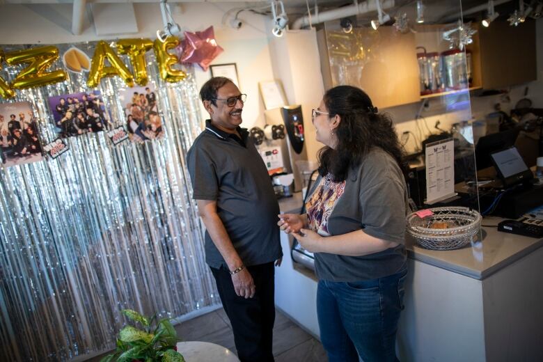 Two people smile at each other in a room decorated with balloons and sparkles