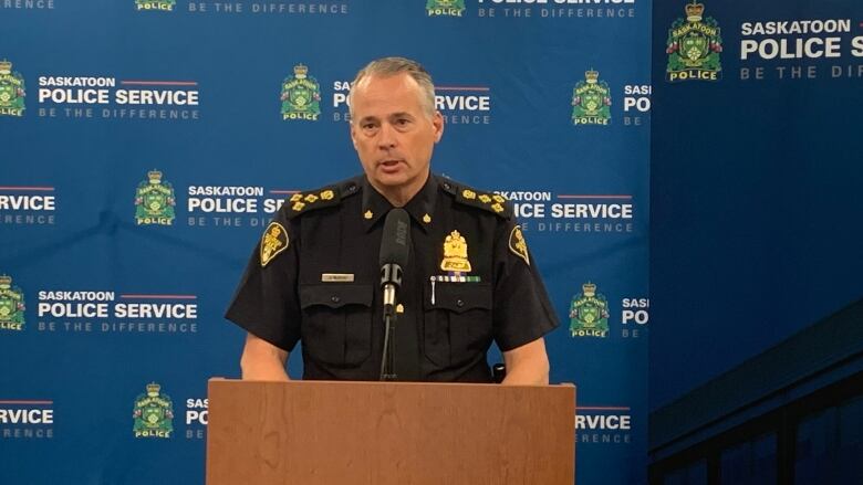 A man in a police uniform stands at a podium during a press conference.