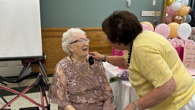 Phyllis Gaetz is smiling as a friend embraces her at her birthday party.