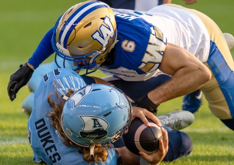 A football player is laid on top of another player from an opposing team.