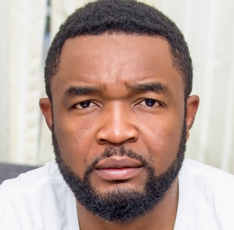 Black man with short hair, goatee and beard wearing white t-shirt