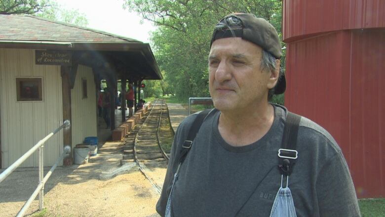 A man wearing a baseball cap and overalls.