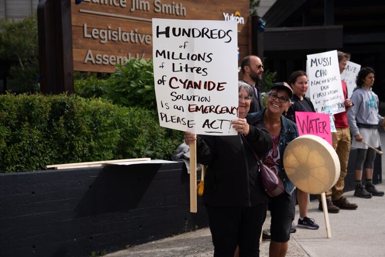 People show their signs to the camera at a protest 