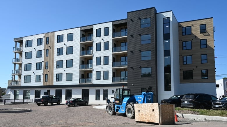 A multi-storey building with a mobile crane parked in front.