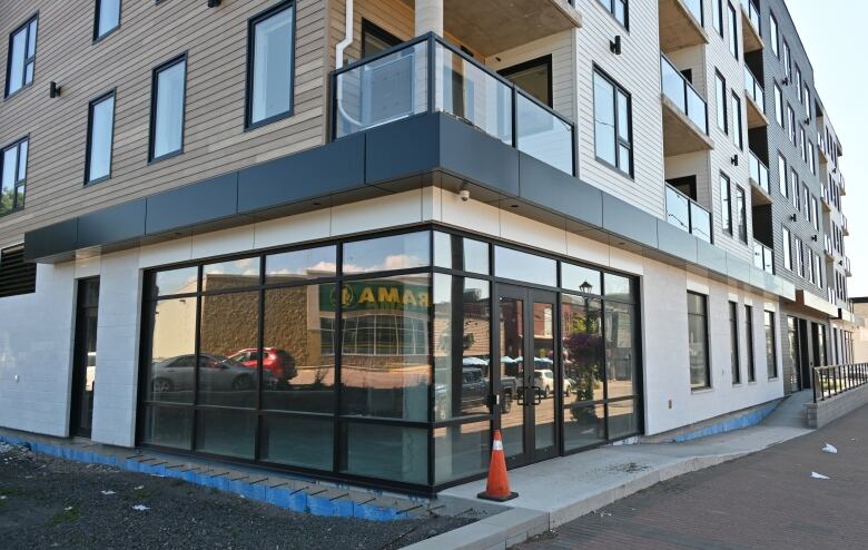 A glass wall of a multi-storey building reflecting adjacent storefronts.