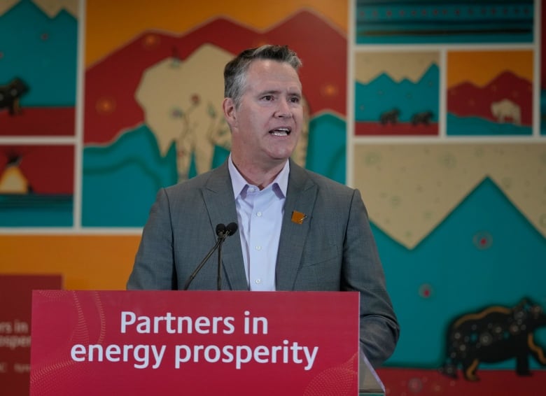 Franois Poirier speaks to an audience standing in front a podium that says partners in energy prosperity. He's wearing a jacket and dress shirt.