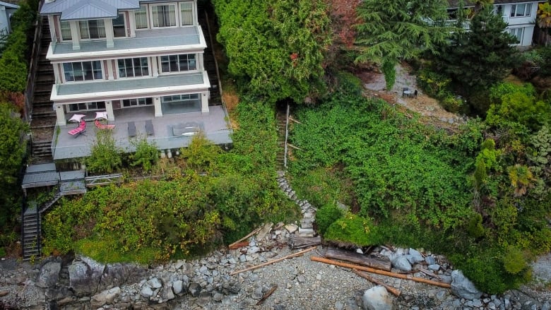 An aerial view of a path leading down a slope beside a three-storey home.