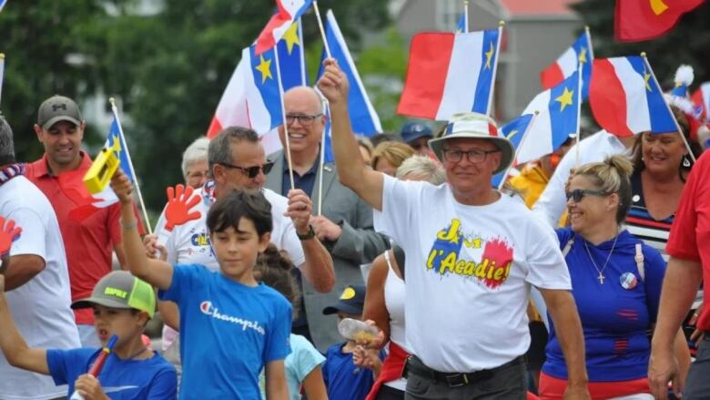 A crowd of people dressed in red, blue and white wave flags.