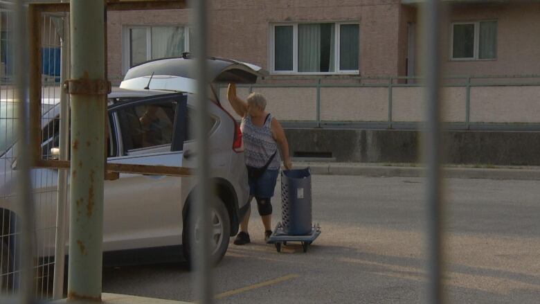 a woman puts stuff in a vehicle. 