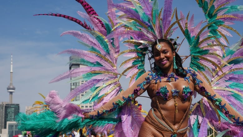 A woman wearing a huge feathery ensemble smiles for a photo at the Toronto Caribbean Carnival.