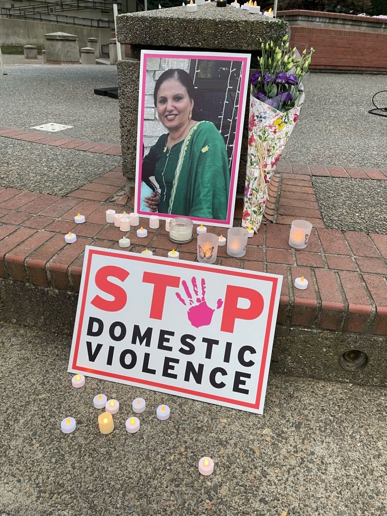 A poster calls for an end to domestic violence in front of a picture of a slain woman.