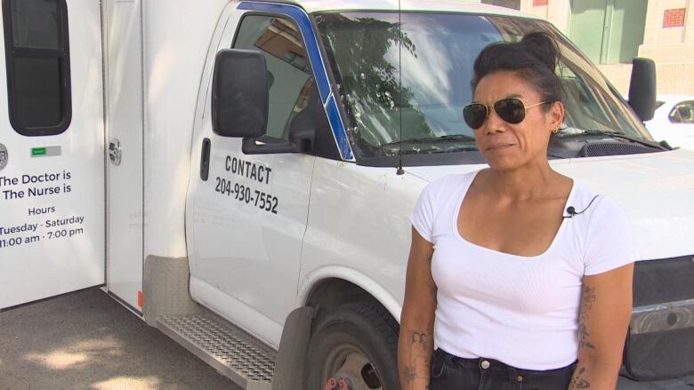 A woman standing in front of a white van.