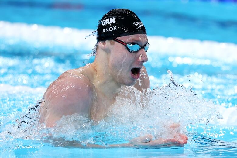 Male swimmer coming up for air, competing in the pool