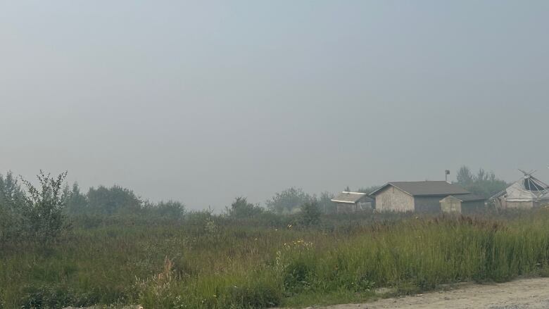 Houses sit on a field covered with wildfire smoke.