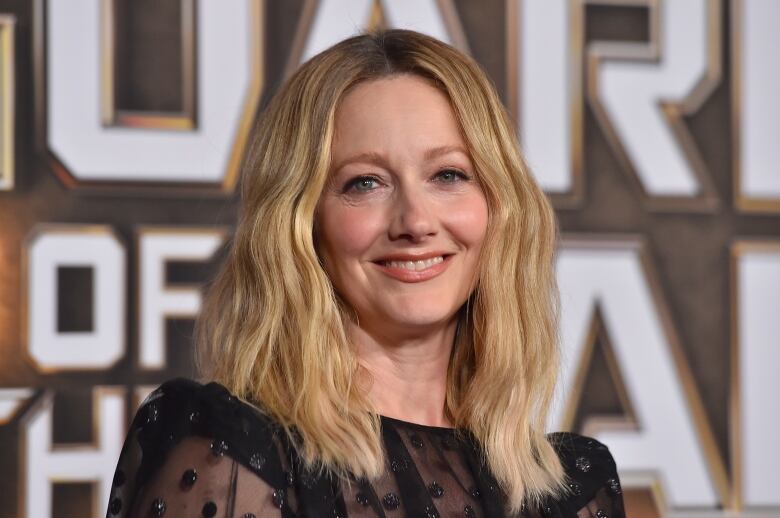 A woman with long blond hair smiles.