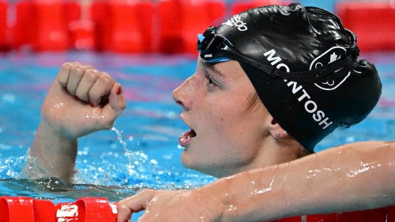 A woman's swimmer raises her fist after a win.