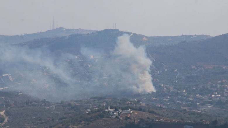 Smoke rises over building located on a hill.