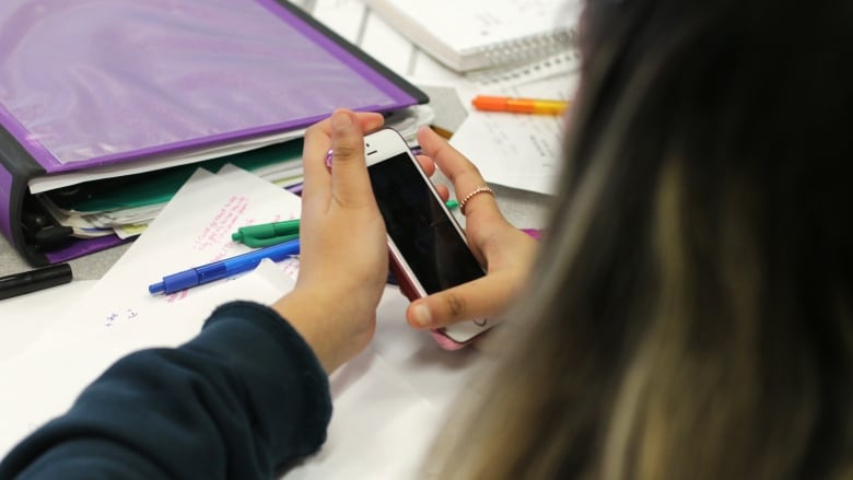 Teenagers are shown on cellphones, in closeup. 