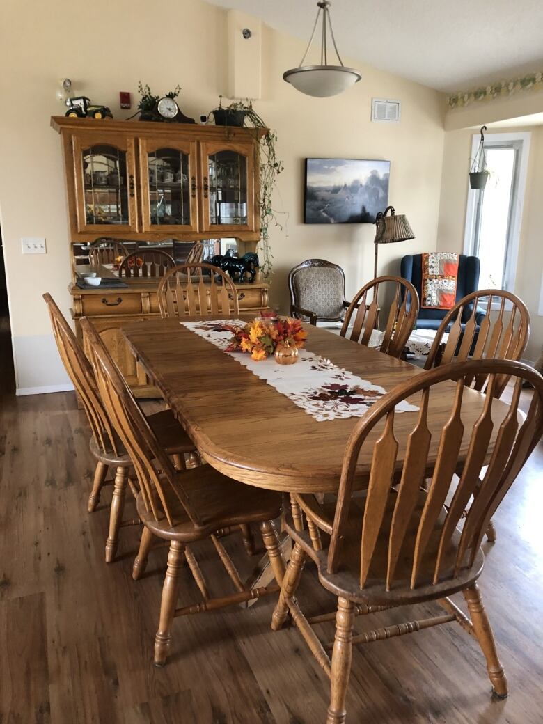 A wooden dining room table with a wooden cabinet behind it.