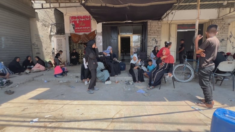 A crowd gathers on the sidewalk in Gaza. 