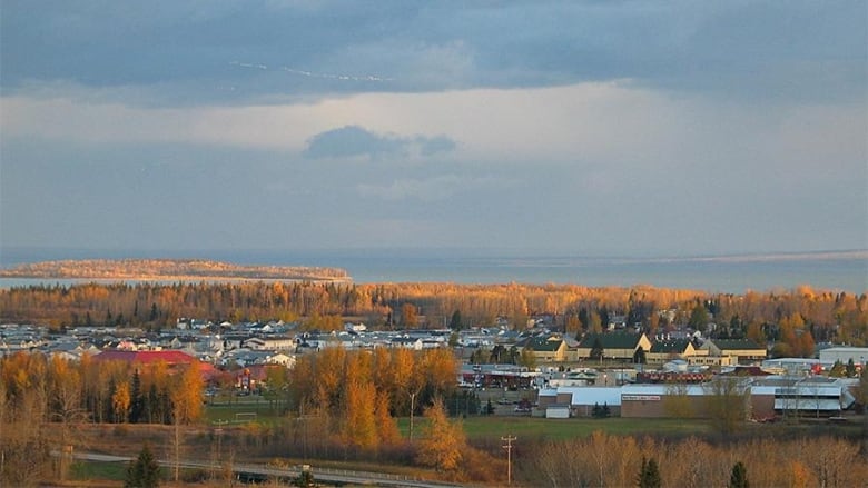 A landscape photo of a small buildings surrounded by a lake and trees.