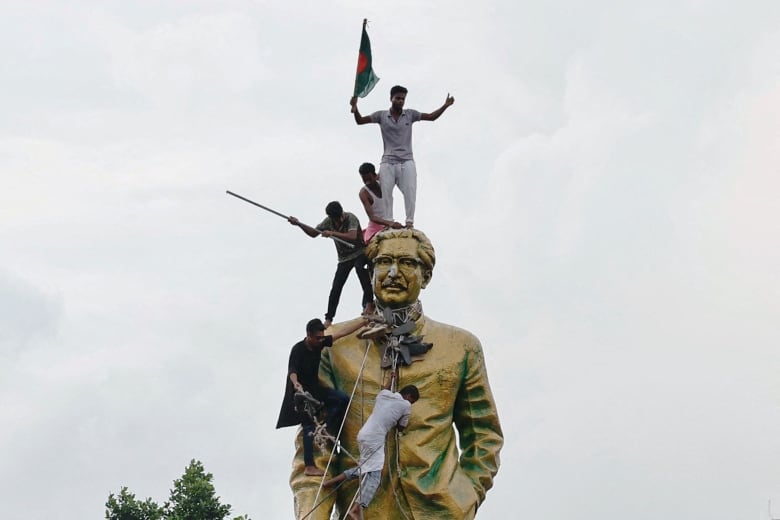 Five men climb a tall statue.