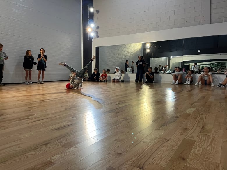 A young boy breakdances in front of a class. 