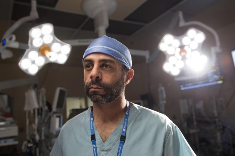 Doctor stands in front of lights in surgical room.