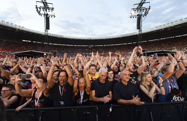 Concertgoers clap and cheer in a stadium.