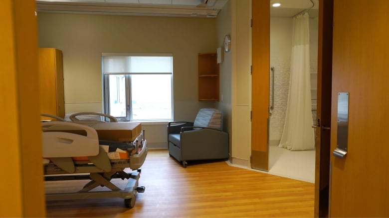 A hospital room, which includes a bed, chair and bathroom. 