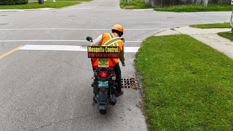 A man of a scooter with a 'mosquito control' sign on the back