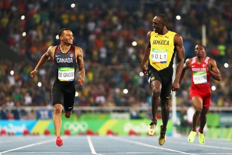 Two sprinters smile at each other mid-race.