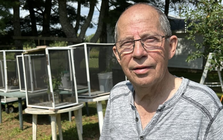 A white man with grey hair on sides, wears glasses.