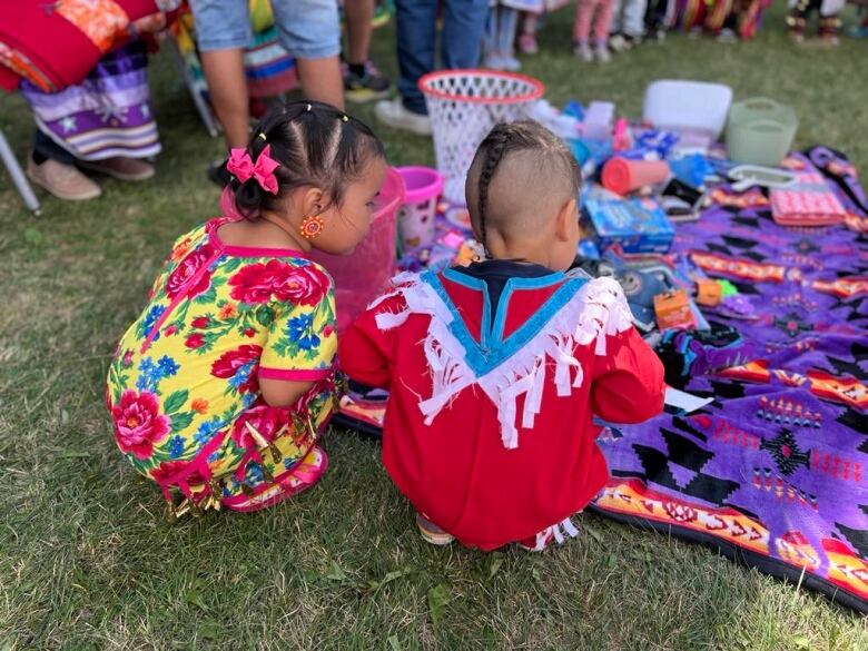 Two small children hovering over a blanket at an initiation ceremony. 