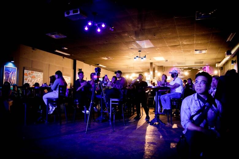 People in a dark space looking at a stage