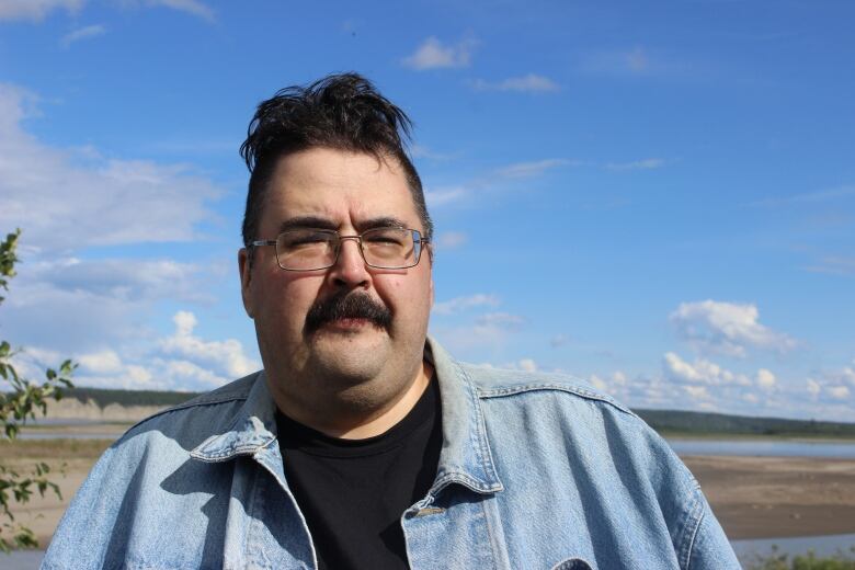 A man with glasses and a jean jacket.