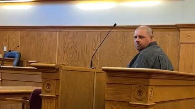 A man sits in the dock in a courtroom. 