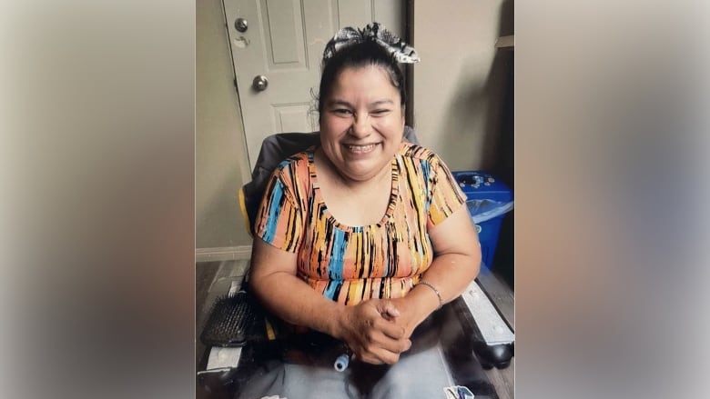 A woman smiles sitting in a wheelchair. 