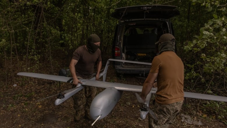 Ukrainian miliary members carry a reconnaissance drone at a position in Ukraine's Sumy region, near the Russian border, on Sunday.