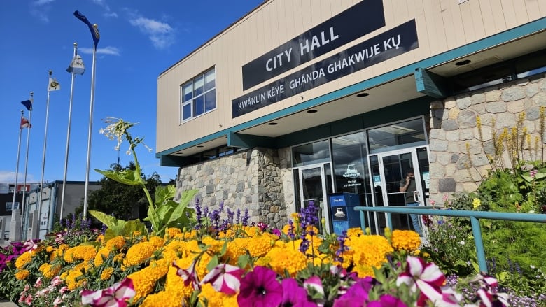 Colourful flowers in the foreground, flags of First Nations, Yukon, Canada, entrance to Whitehorse city hall