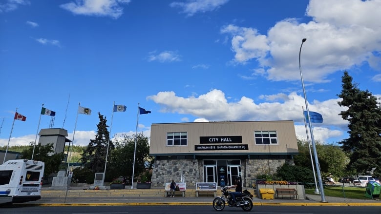 A motorcycle goes past Whitehorse City Hall.