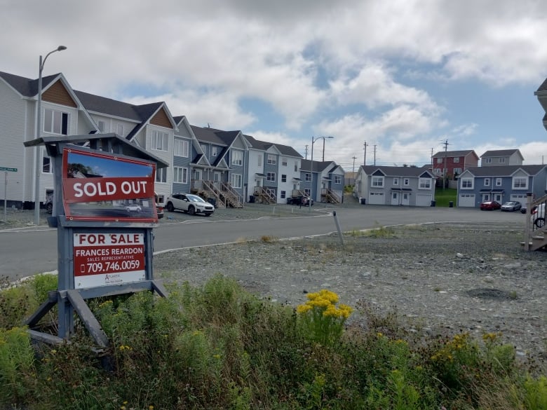 A for sale sign that says sold out next to a cul-de-sac that isn't finished and where front of homes are just gravel.