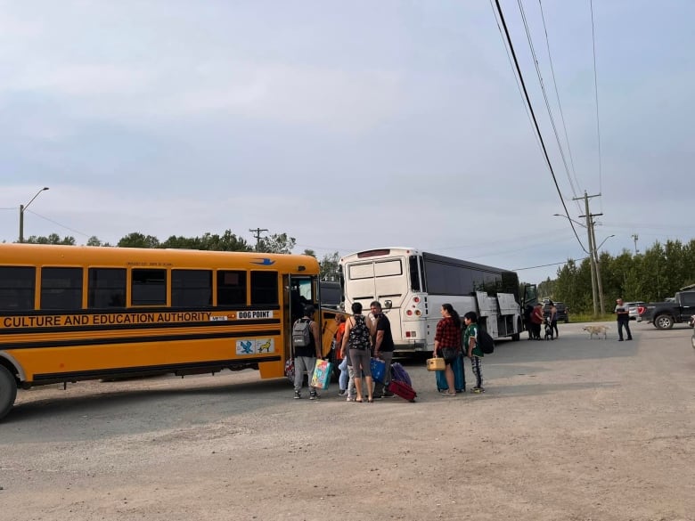 A group of people stand outside of a bus 