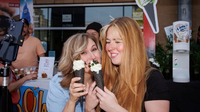 Two smiling women each holding chocolate-coloured cones with green wasabi ice cream