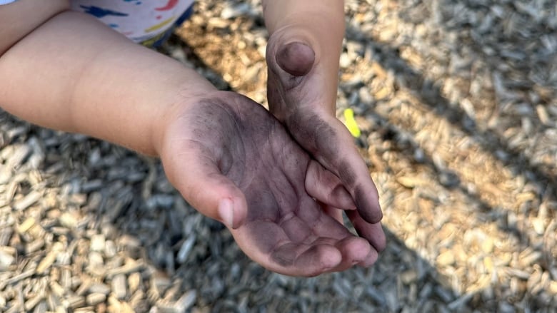 Child's hands with black on them